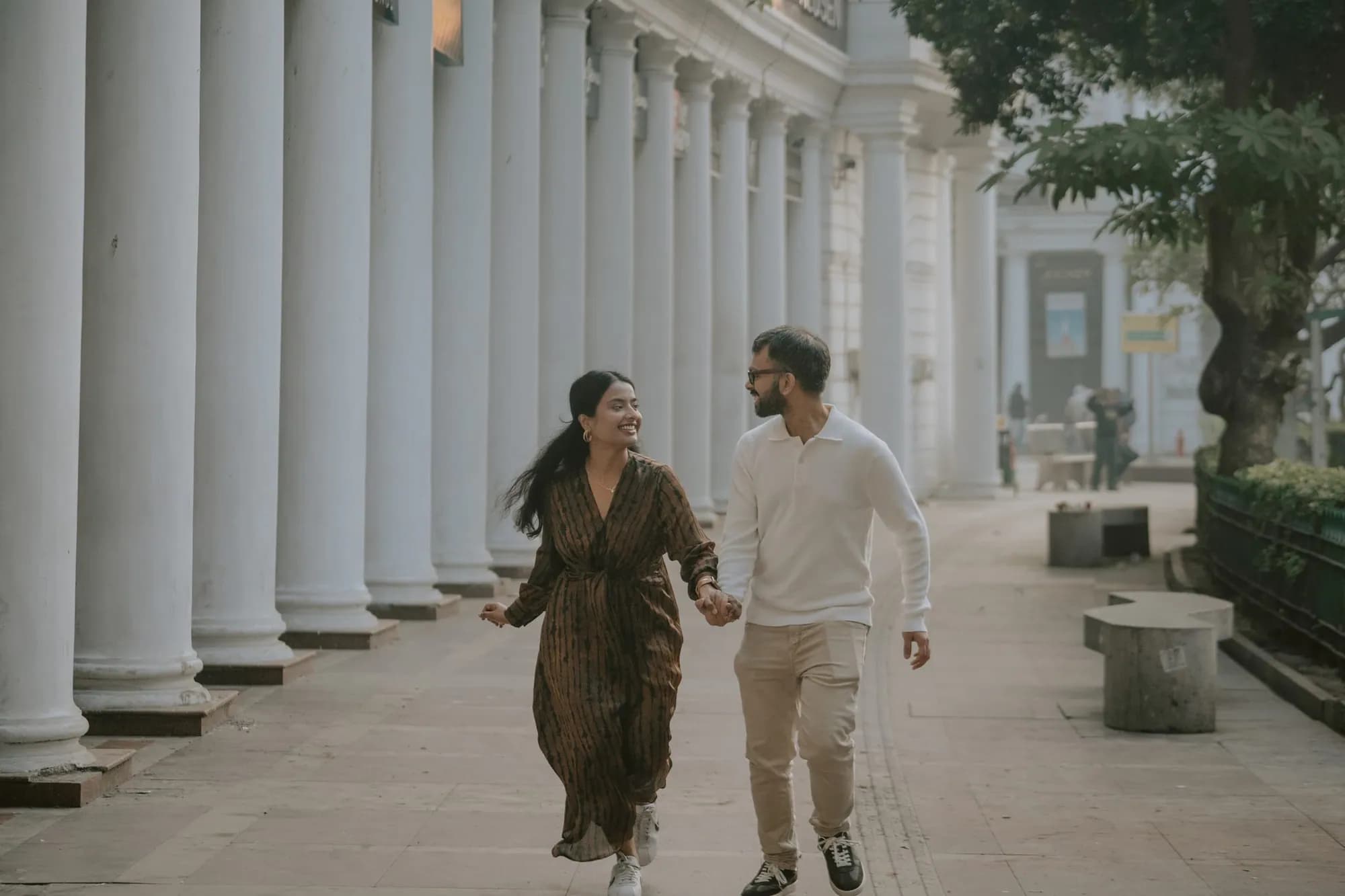 Couple running through a long colonnade, wide frame